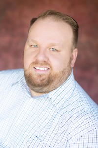 Image of a bearded man in a button up shirt.
