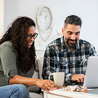 A couple viewing a laptop computer in their living room