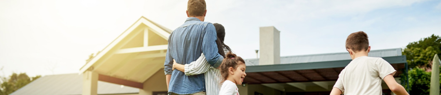 a family of 4 standing outside their new house