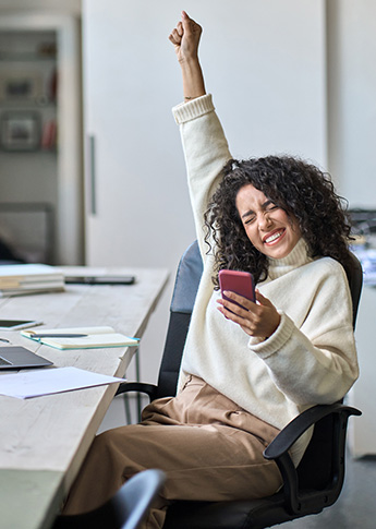 Young woman holding phone and putting up arm in celebration